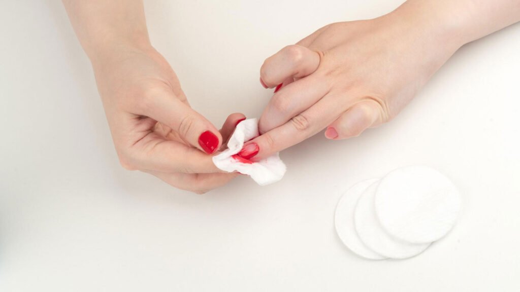 woman removing nail polish with acetone cloth